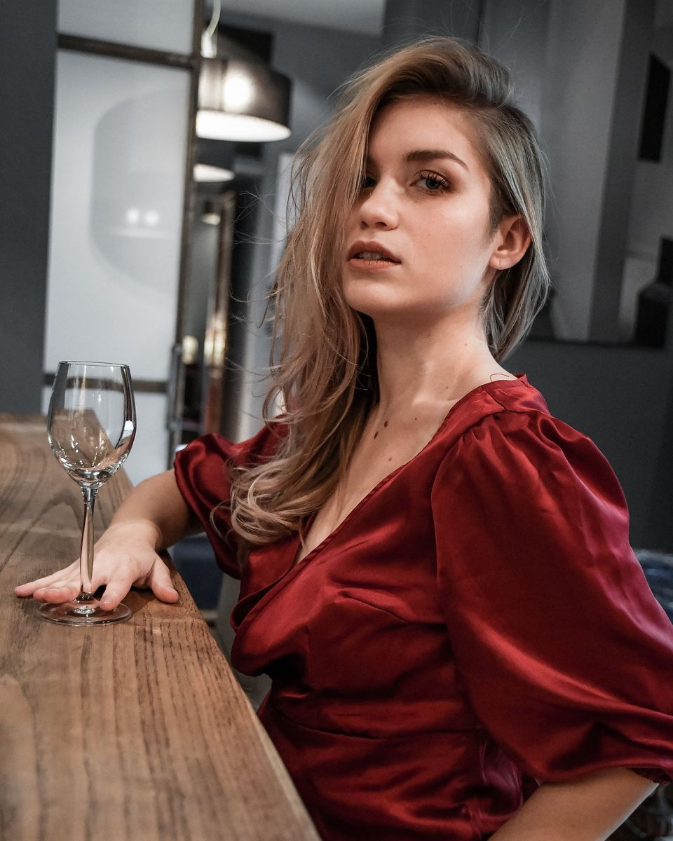 Woman in a burgundy velvet plunge-neck dress seated at a bar