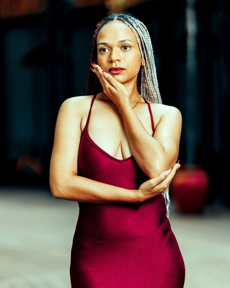 Woman in a burgundy satin slip maxi dress posing indoors