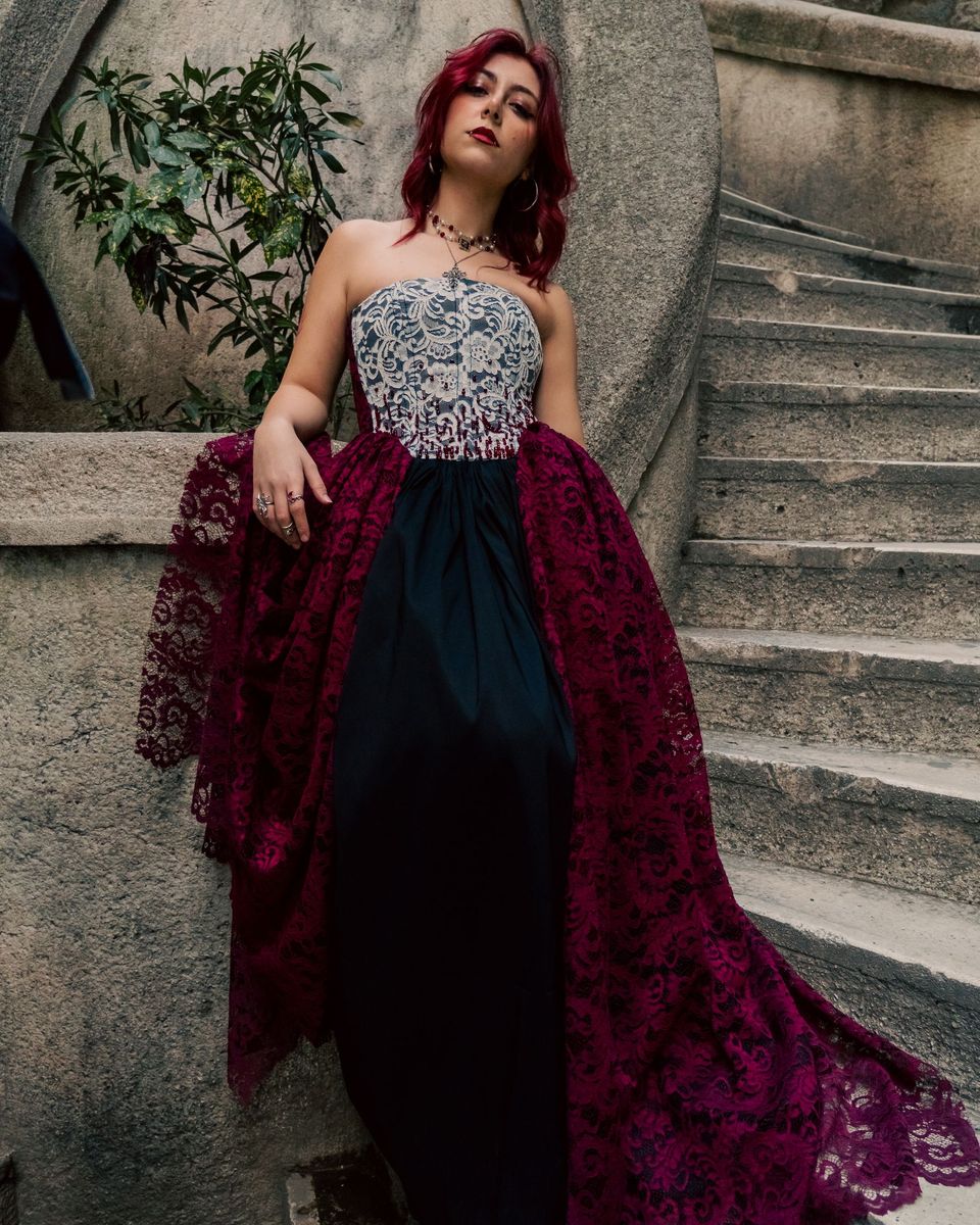 Woman in a maroon evening gown with an embellished bodice on a stone staircase