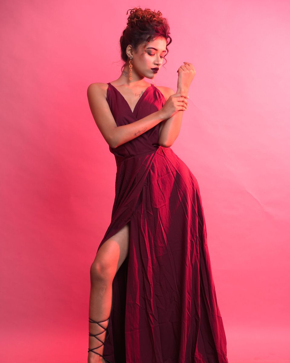 Woman in a burgundy wrap maxi gown with a leg slit