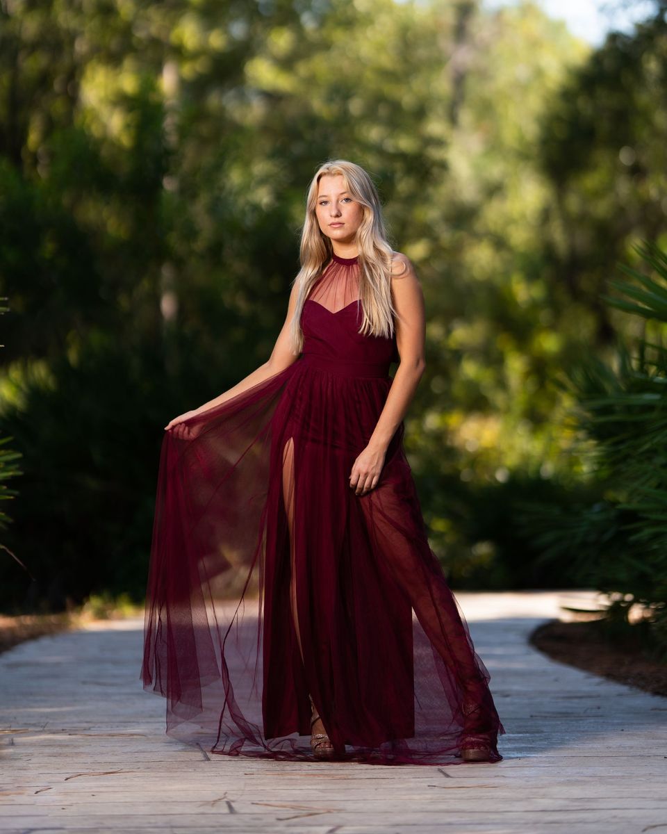 Woman in a flowing maroon chiffon maxi dress on a wooded path