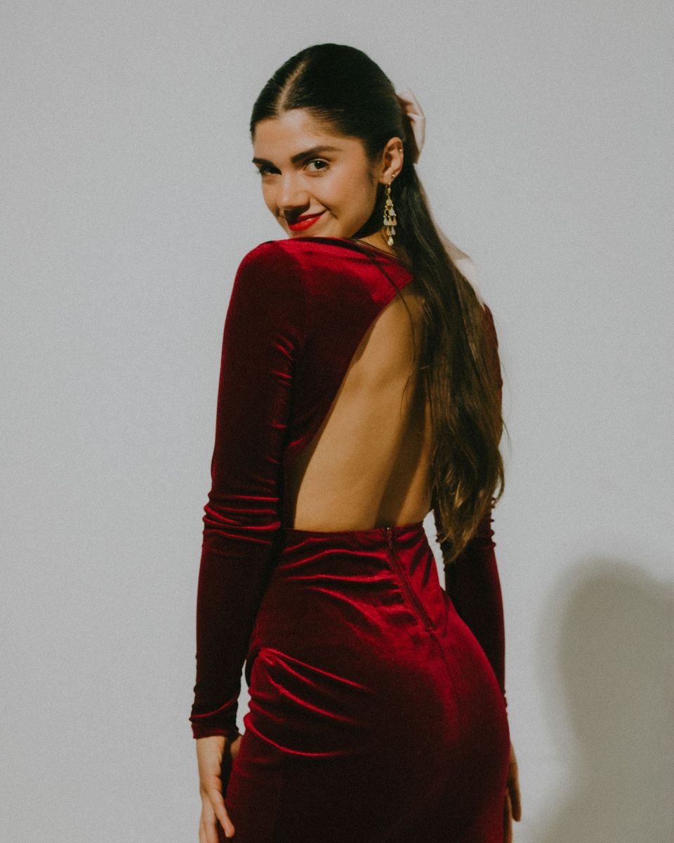 Woman showing the open back of a burgundy velvet maxi dress